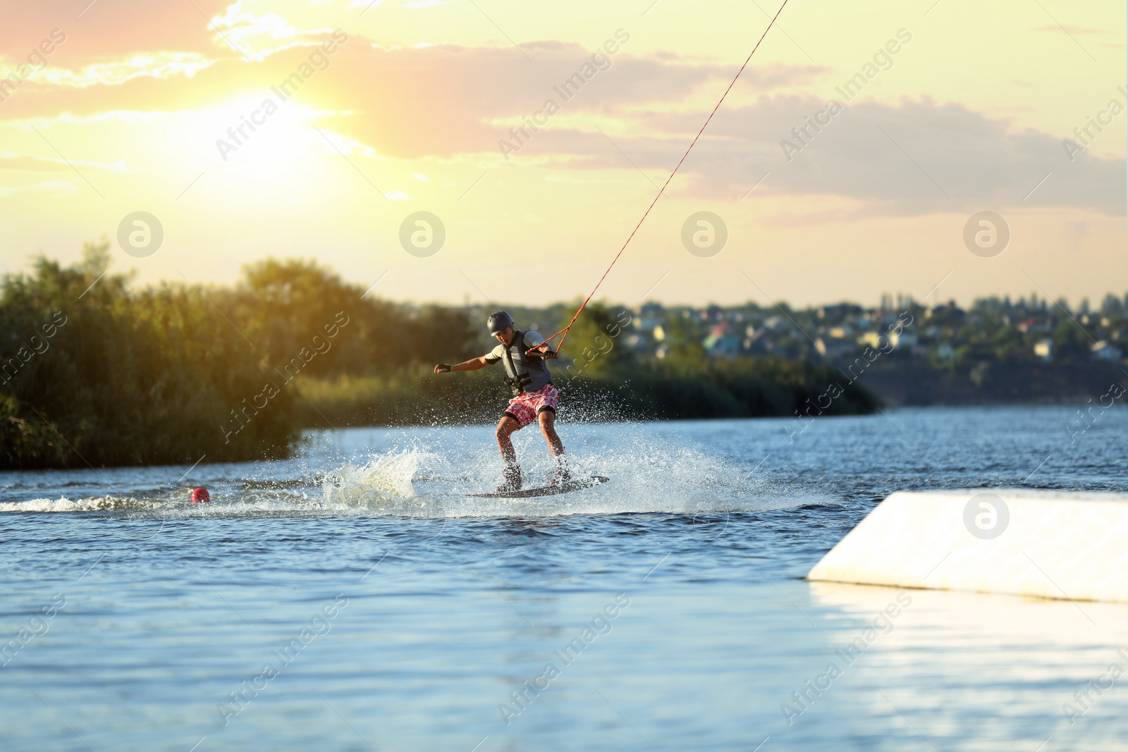 Photo of Teenage boy wakeboarding on river. Extreme water sport