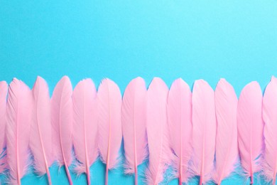 Photo of Beautiful pink feathers on light blue background, flat lay. Space for text