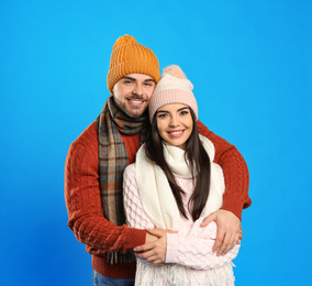 Happy young couple in warm clothes on blue background. Winter vacation