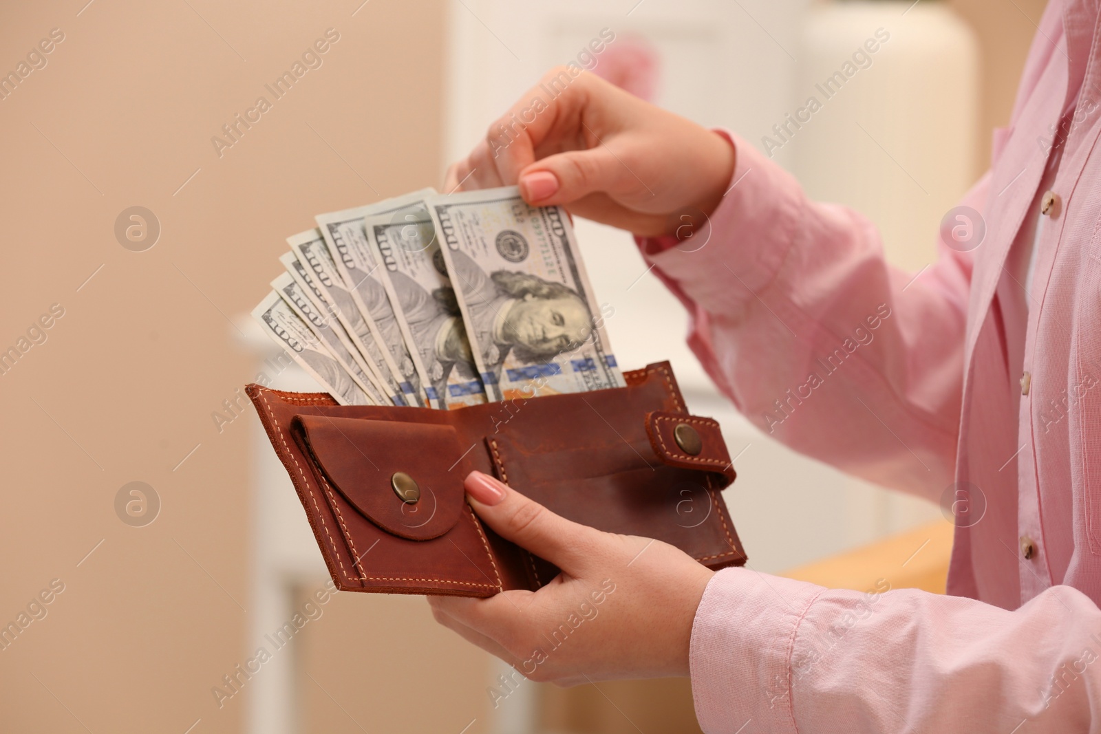 Photo of Woman counting dollar bills indoors, closeup. Money exchange