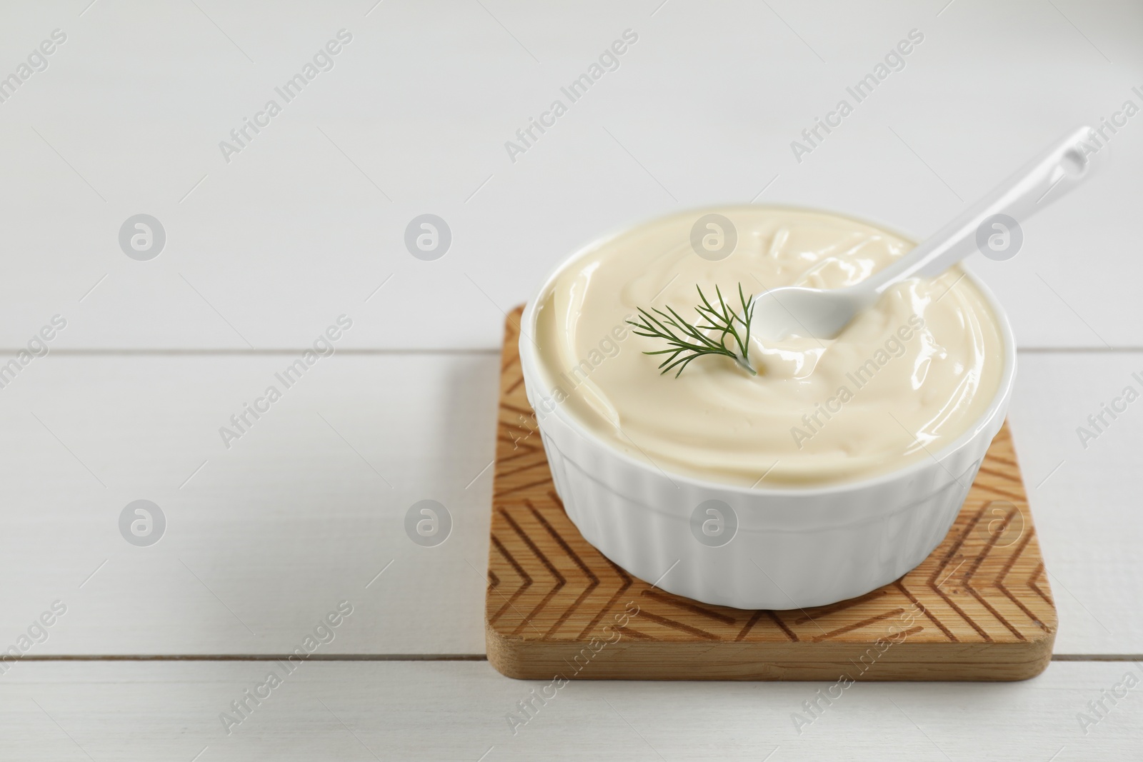 Photo of Fresh mayonnaise sauce in bowl on white wooden table. Space for text