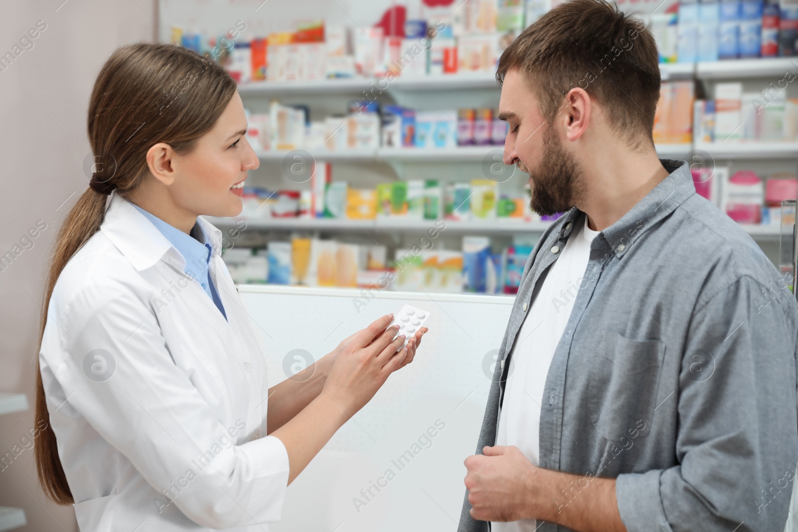 Photo of Professional pharmacist working with customer in modern drugstore