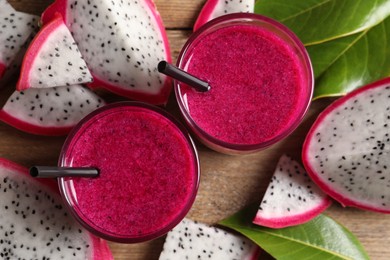Photo of Delicious pitahaya smoothie and fresh fruits on wooden table, flat lay