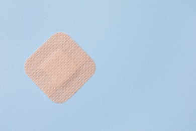 Contraceptive patch on light blue background, top view. Space for text