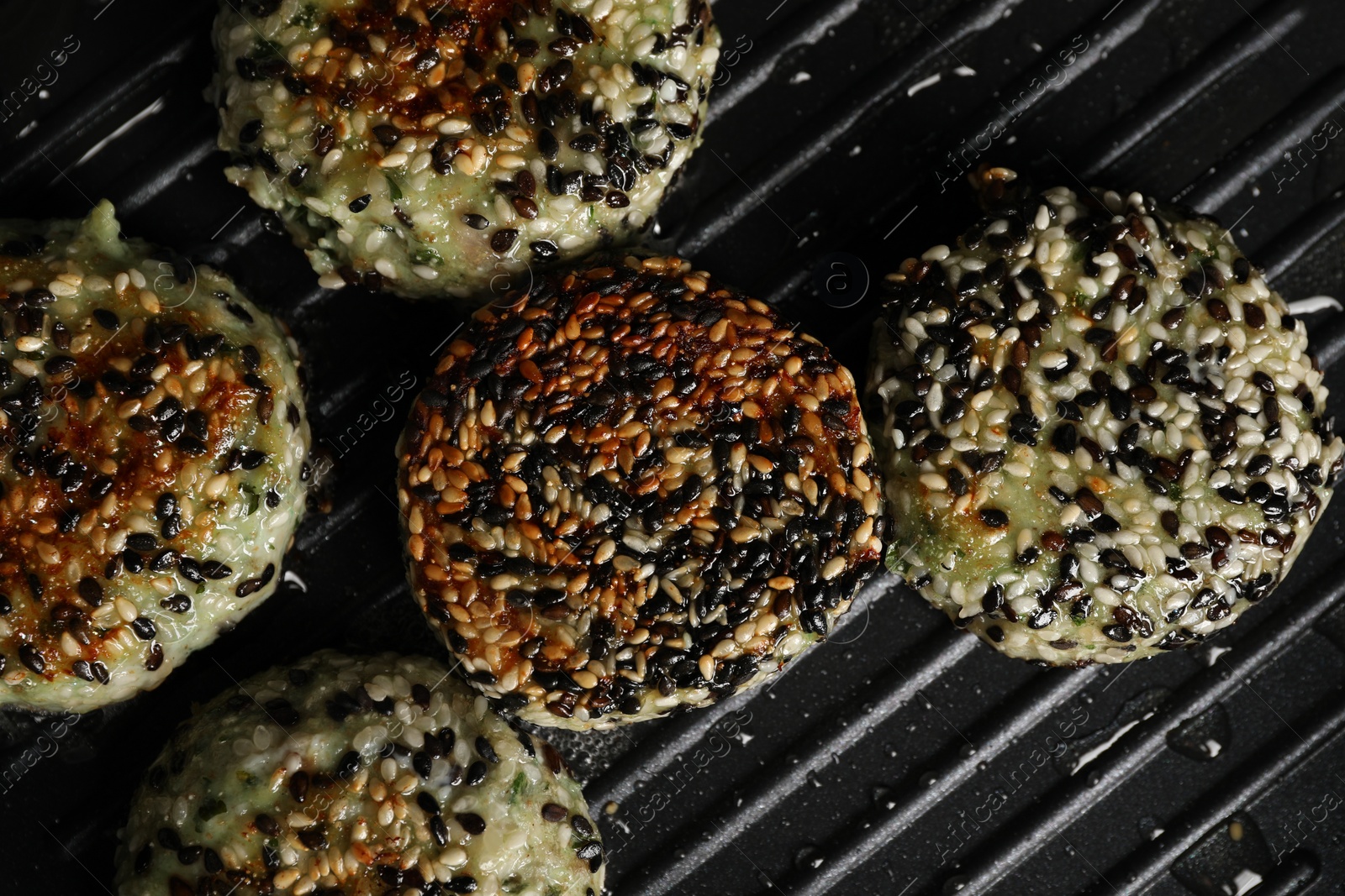 Photo of Cooking tasty vegan cutlets with sesame in grill pan, top view