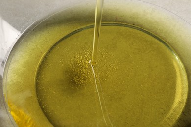 Photo of Pouring cooking oil into bowl, closeup view