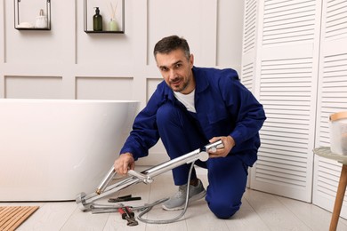 Professional plumber installing water tap in bathroom