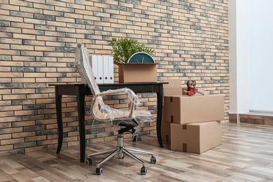 Photo of Furniture and moving boxes in empty office