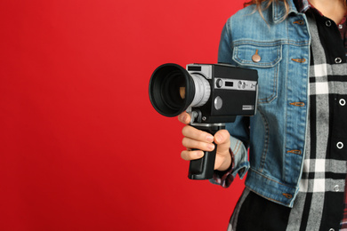 Photo of Woman with vintage video camera on red background, closeup. Space for text