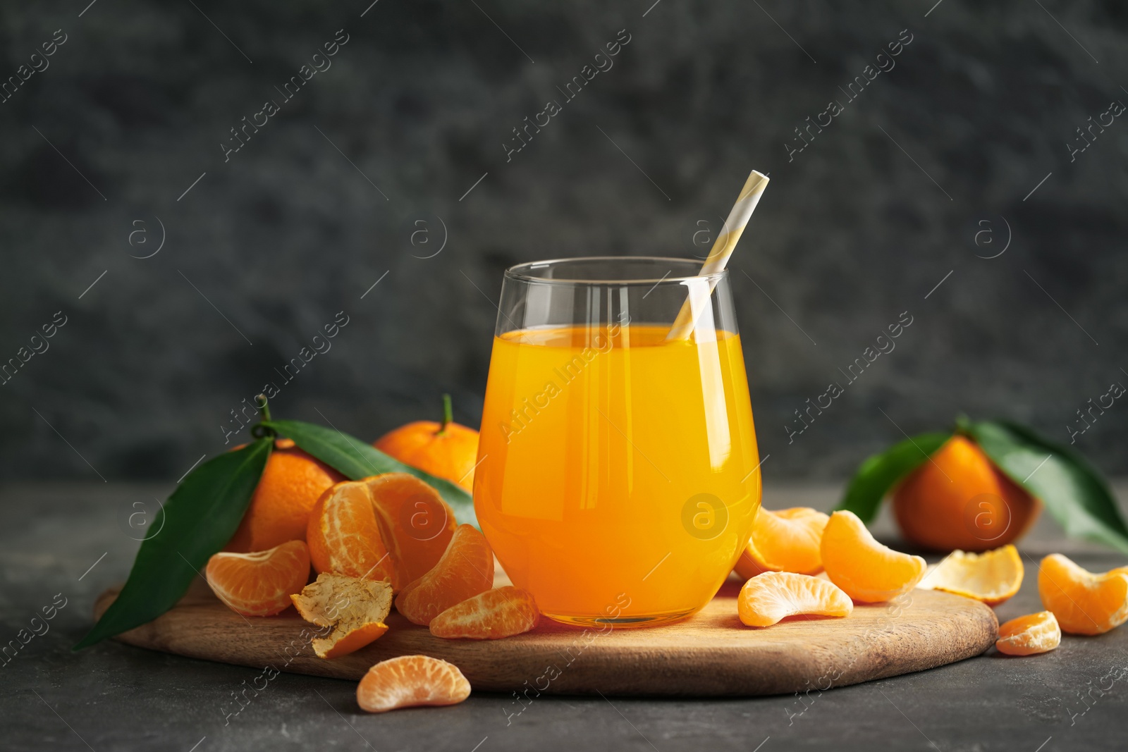 Photo of Fresh tangerines and glass of juice on grey table