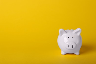 Ceramic piggy bank on yellow background, space for text. Financial savings