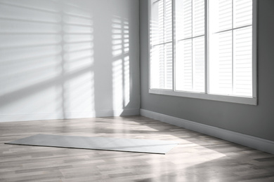 Photo of Unrolled grey yoga mat on floor in room