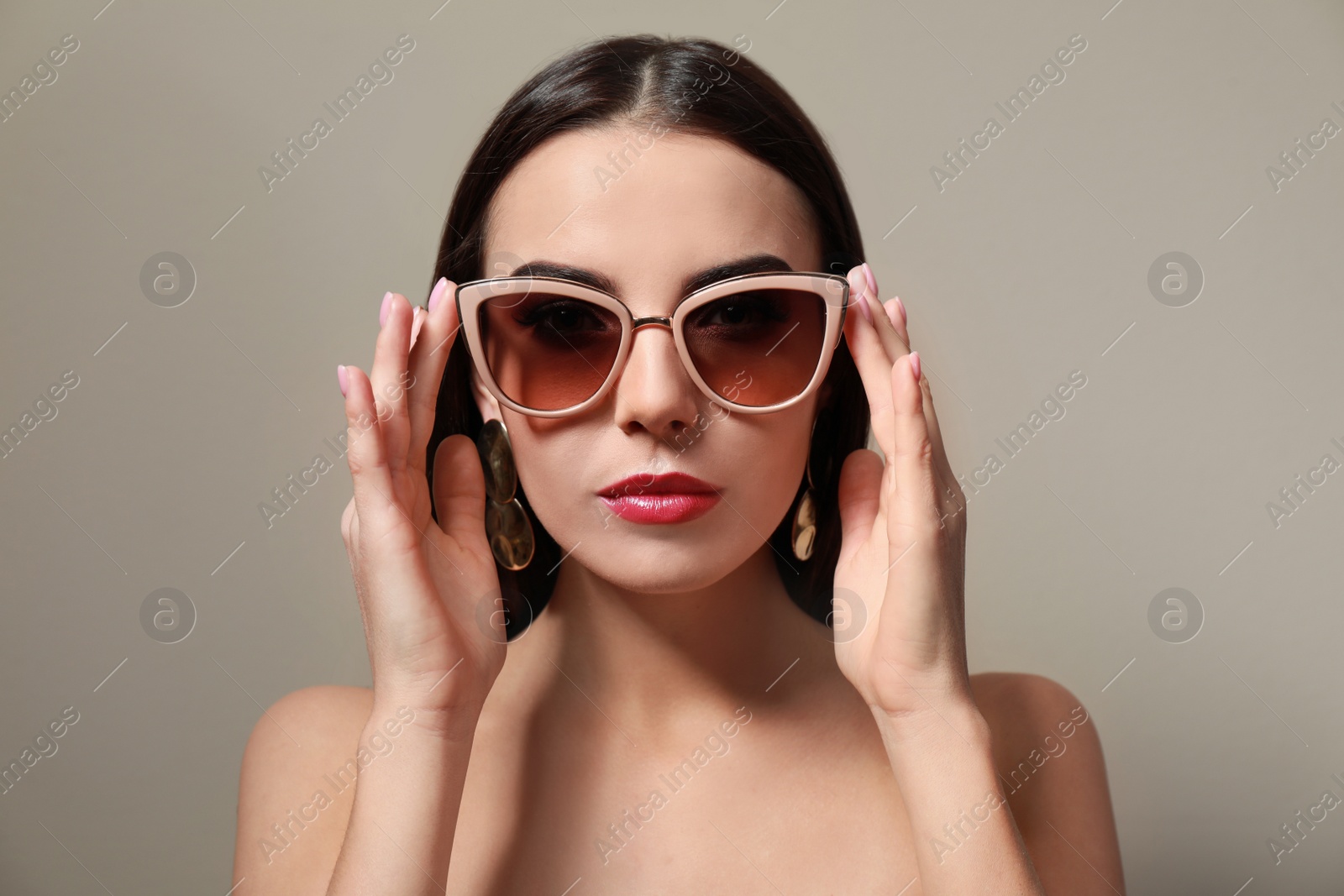 Photo of Beautiful woman in stylish sunglasses on beige background