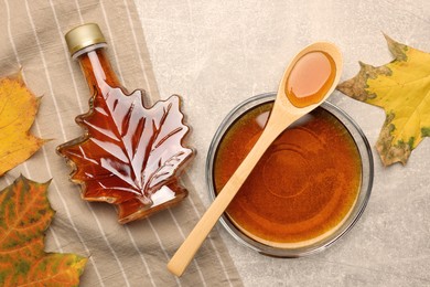 Flat lay composition with tasty maple syrup and dry leaves on light grey table