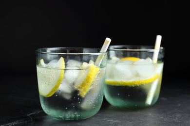 Photo of Soda water with lemon slices and ice cubes on grey table