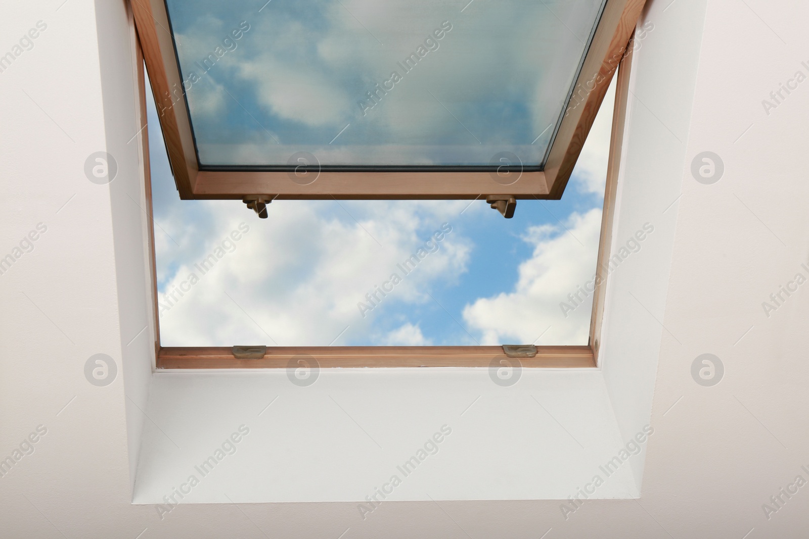 Photo of Open skylight roof window on slanted ceiling in attic room, bottom view