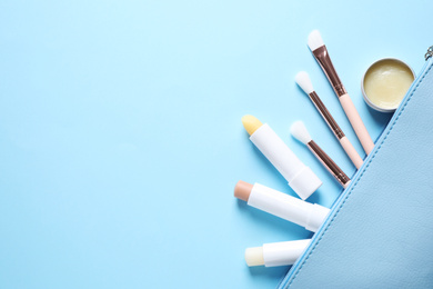 Flat lay composition with hygienic lipsticks on light blue background, space for text