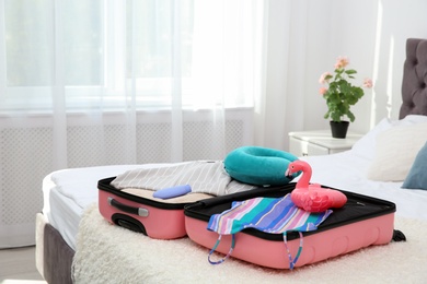 Modern suitcase with clothes packed for journey on bed indoors
