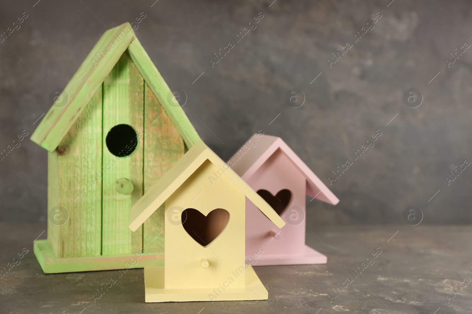 Photo of Beautiful bird houses on grey stone table, space for text