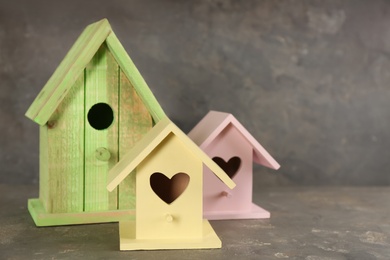 Beautiful bird houses on grey stone table, space for text