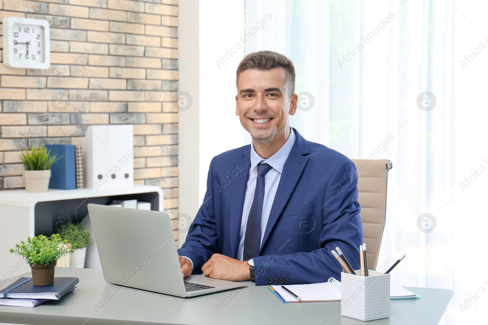 Photo of Man in office wear using laptop at table indoors