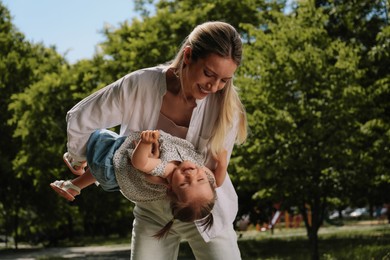 Happy mother with her daughter having fun in park