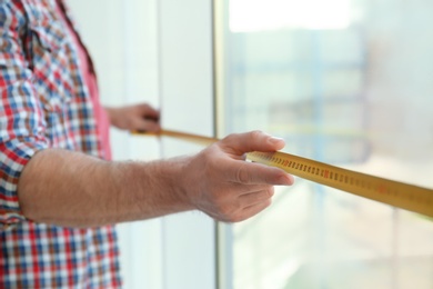 Photo of Man measuring window, closeup view. Construction tool