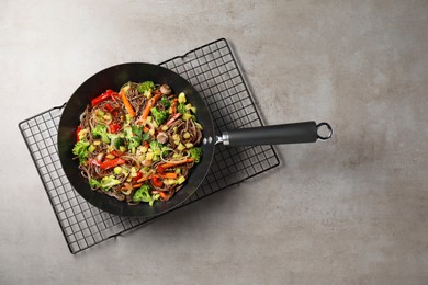 Stir-fry. Tasty noodles with meat and vegetables in wok on grey textured table, top view