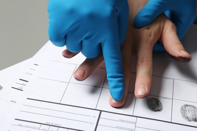 Photo of Investigator taking fingerprints of suspect on table, closeup