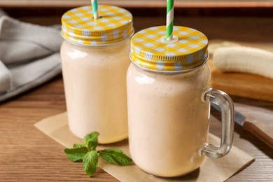 Photo of Tasty banana smoothie and mint on wooden table, closeup