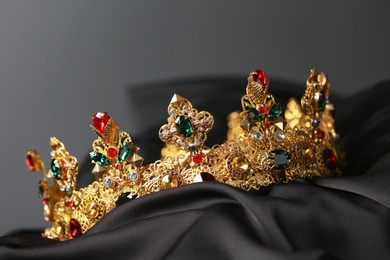 Beautiful golden crown with gems on dark cloth