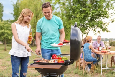 Young people having barbecue with modern grill outdoors