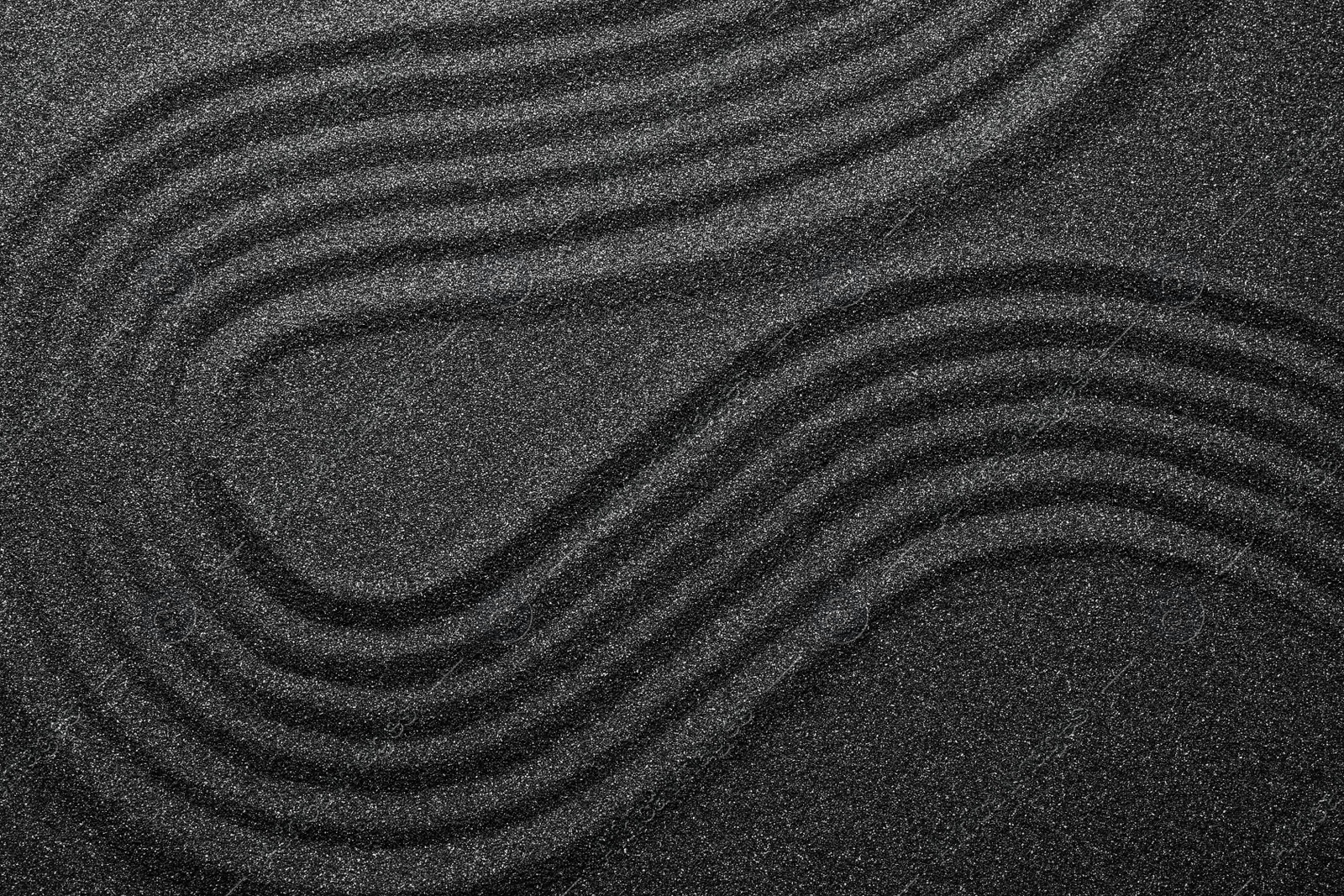 Photo of Black sand with beautiful pattern, top view. Zen concept