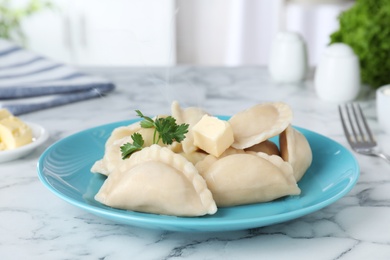 Photo of Plate of tasty dumplings served with parsley and butter on table