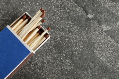 Photo of Open box with matches on grey background, top view. Space for text