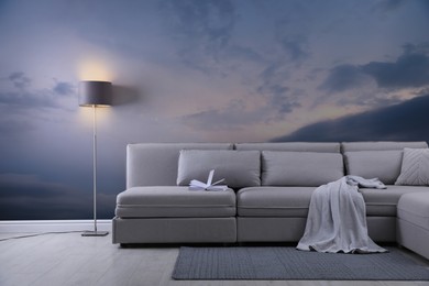 Image of Beautiful sky with clouds as wallpaper pattern. Living room interior with comfortable sofa near wall