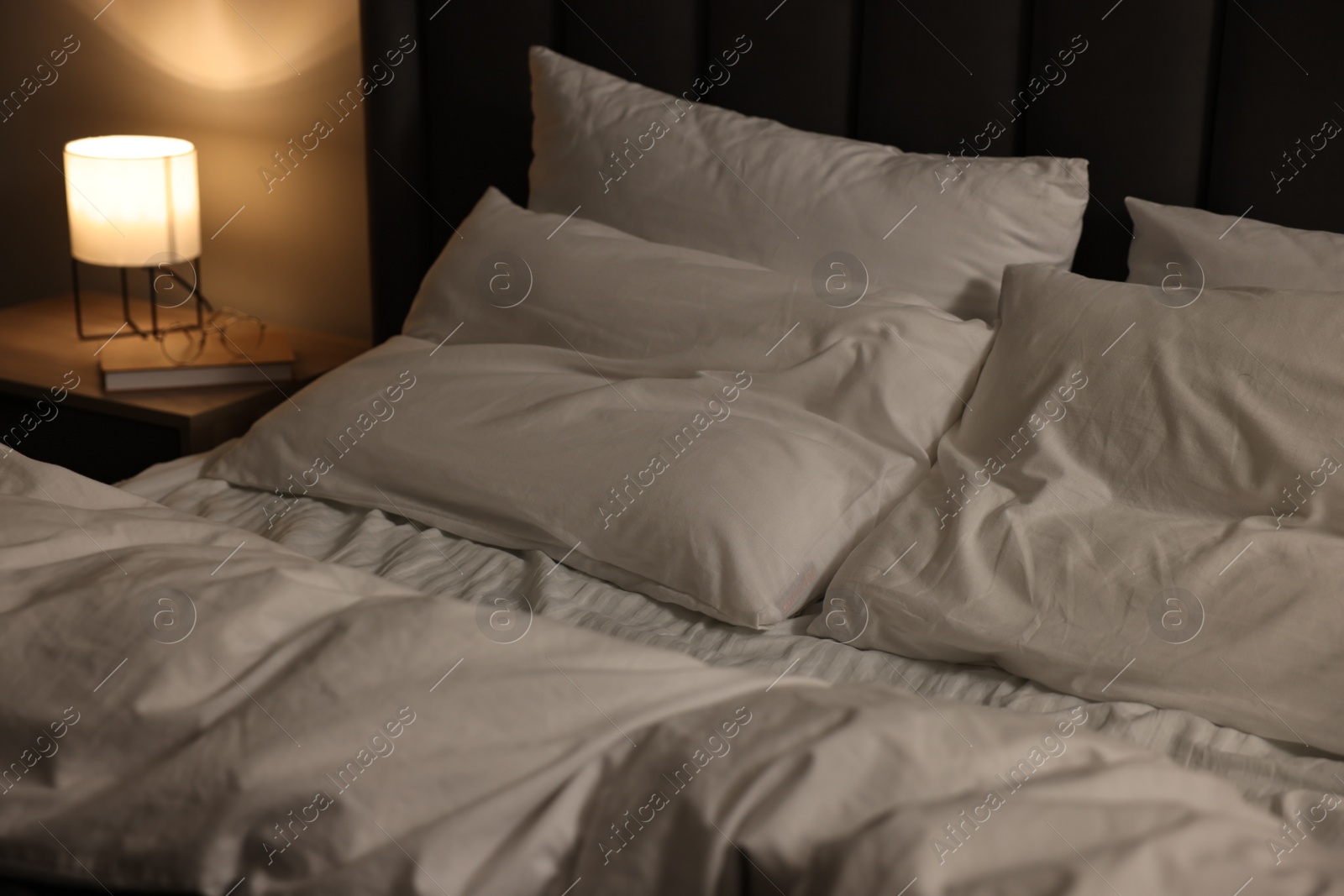 Photo of Soft bed and bedside table with nightlight indoors