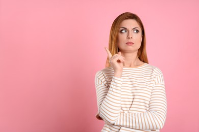 Photo of Pensive woman on pink background, space for text. Thinking about answer to question