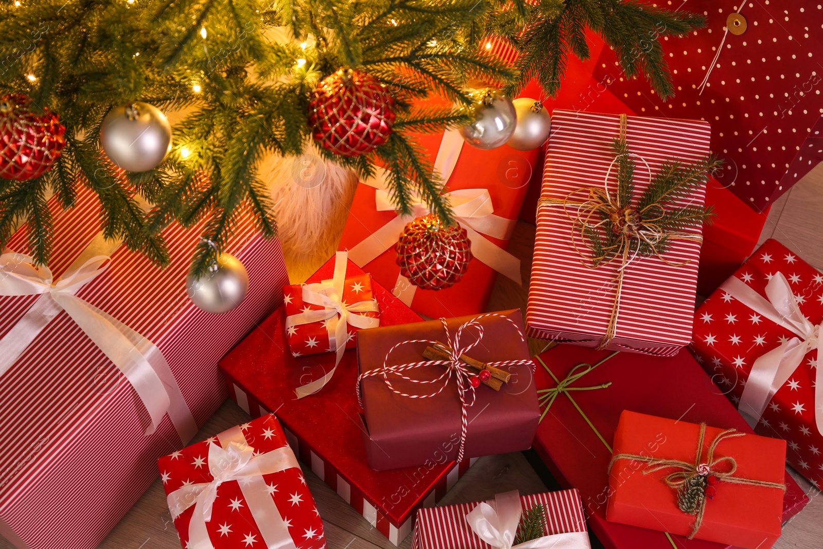 Photo of Pile of gift boxes near Christmas tree on floor