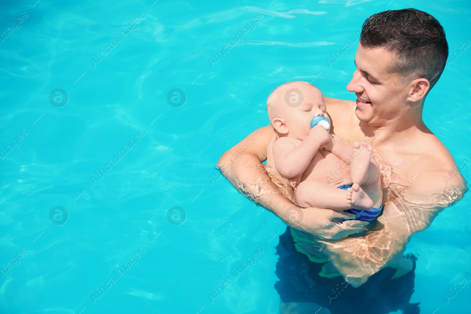 Photo of Man with his little baby in swimming pool on sunny day, outdoors