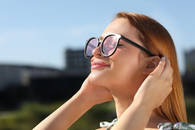 Photo of Beautiful woman in sunglasses outdoors. Space for text