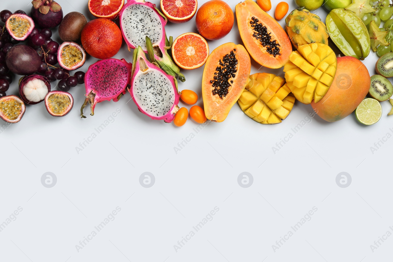 Photo of Many different delicious exotic fruits on light background, flat lay. Space for text