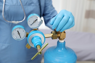 Photo of Medical worker checking oxygen tank in hospital room, closeup