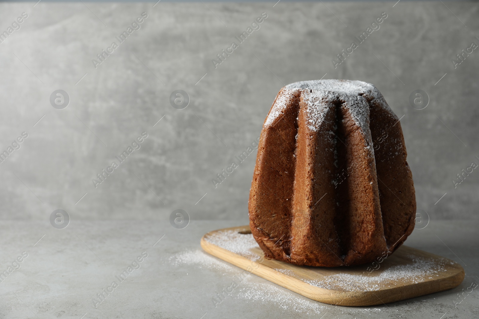 Photo of Delicious Pandoro cake decorated with powdered sugar on light grey table, space for text. Traditional Italian pastry