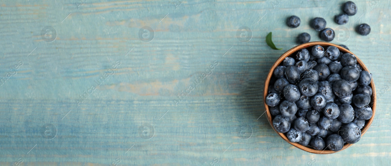 Image of Tasty fresh blueberries on wooden table, top view with space for text. Banner design