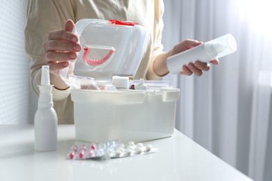 Woman opening first aid kit at white table indoors, closeup