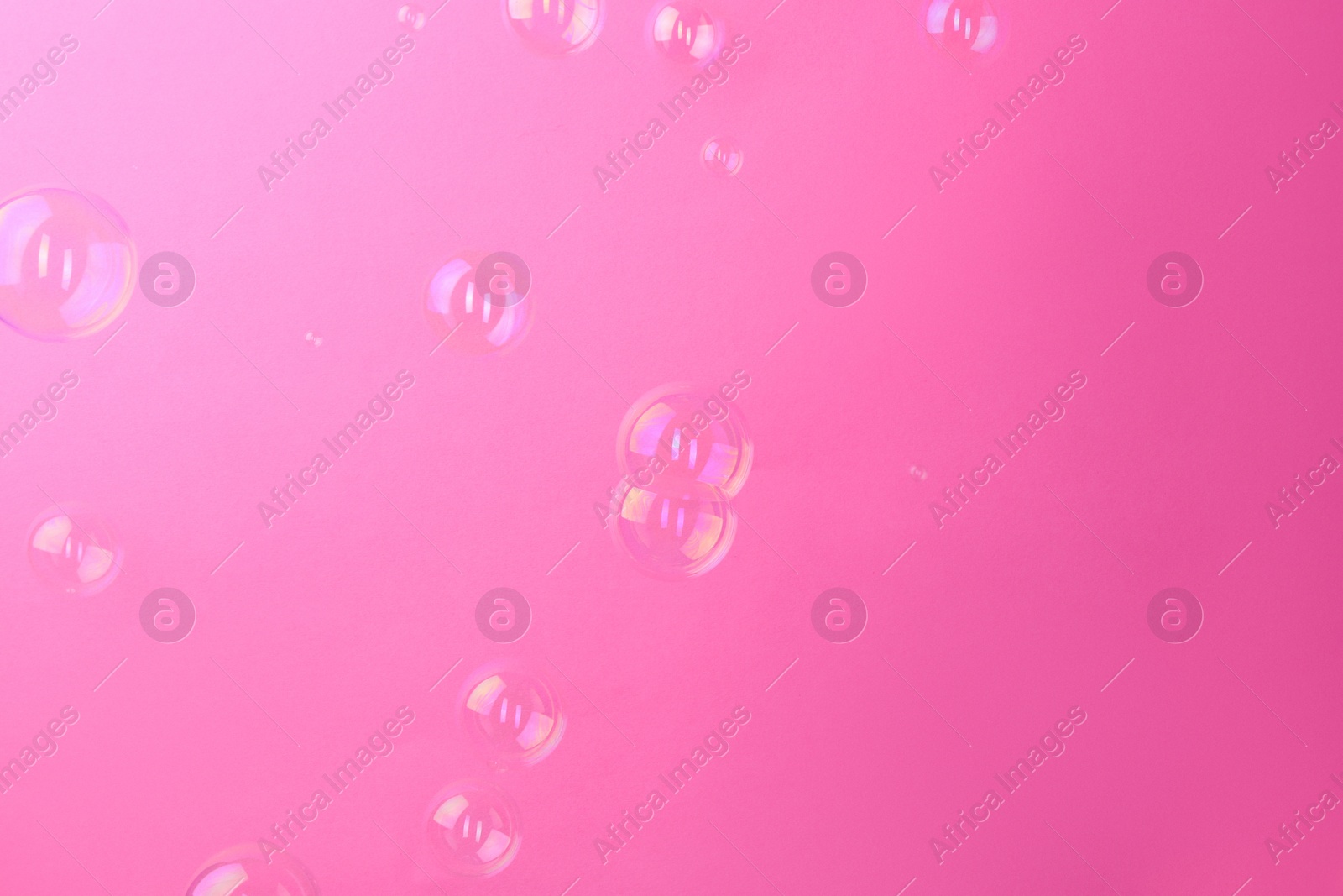 Photo of Beautiful transparent soap bubbles on pink background