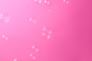 Photo of Beautiful transparent soap bubbles on pink background