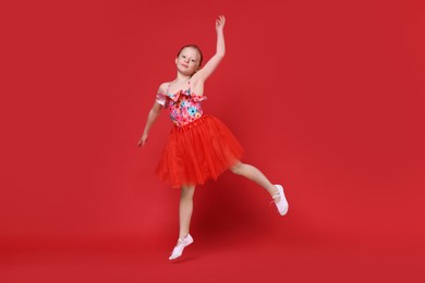 Cute little girl dancing on red background