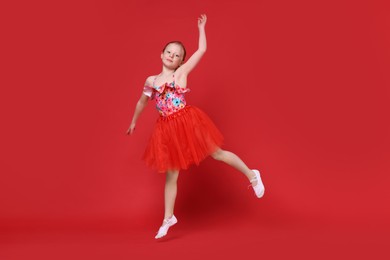 Photo of Cute little girl dancing on red background